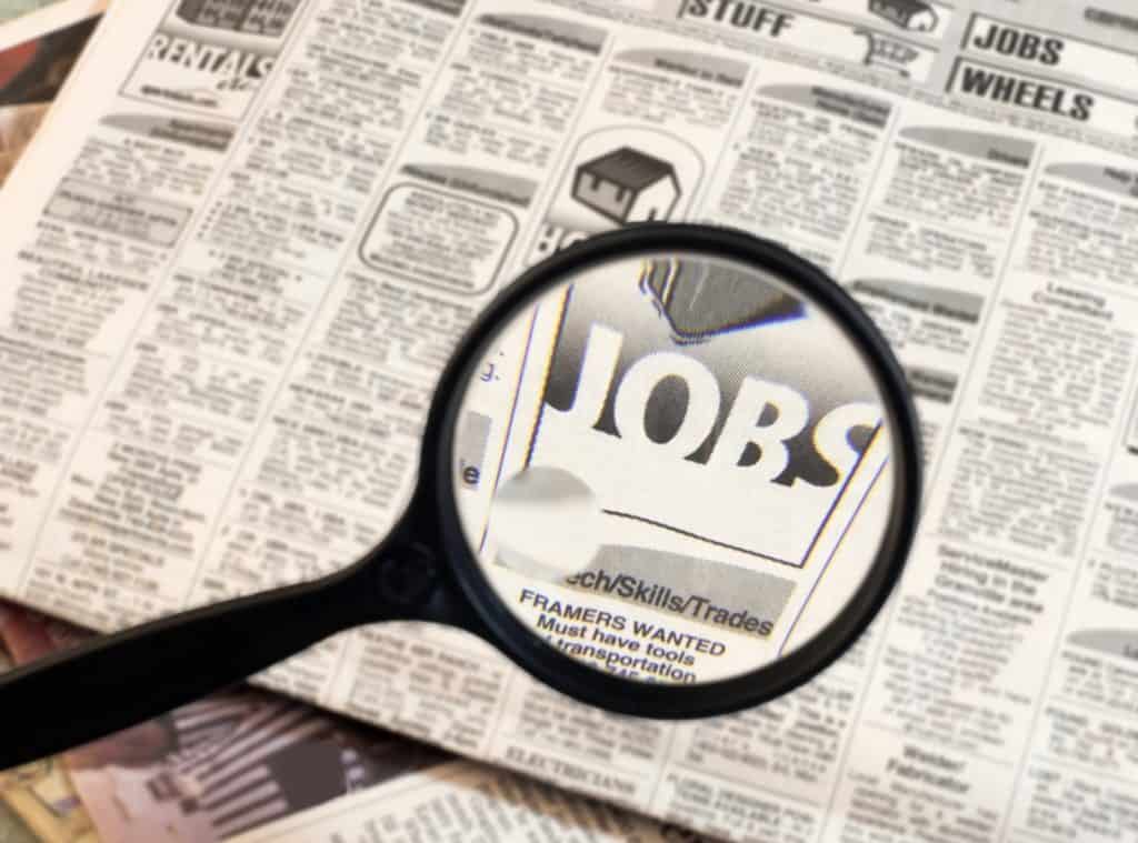 magnifying glass hovering over a newspaper with the word JOBS