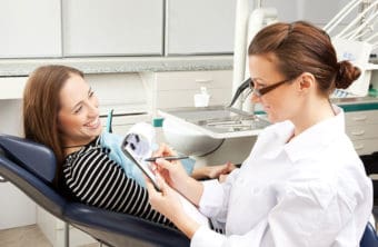Female dental assistant is taking records with patient