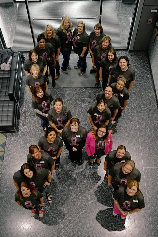 A group of people forming a ribbon forBreast Cancer Awareness