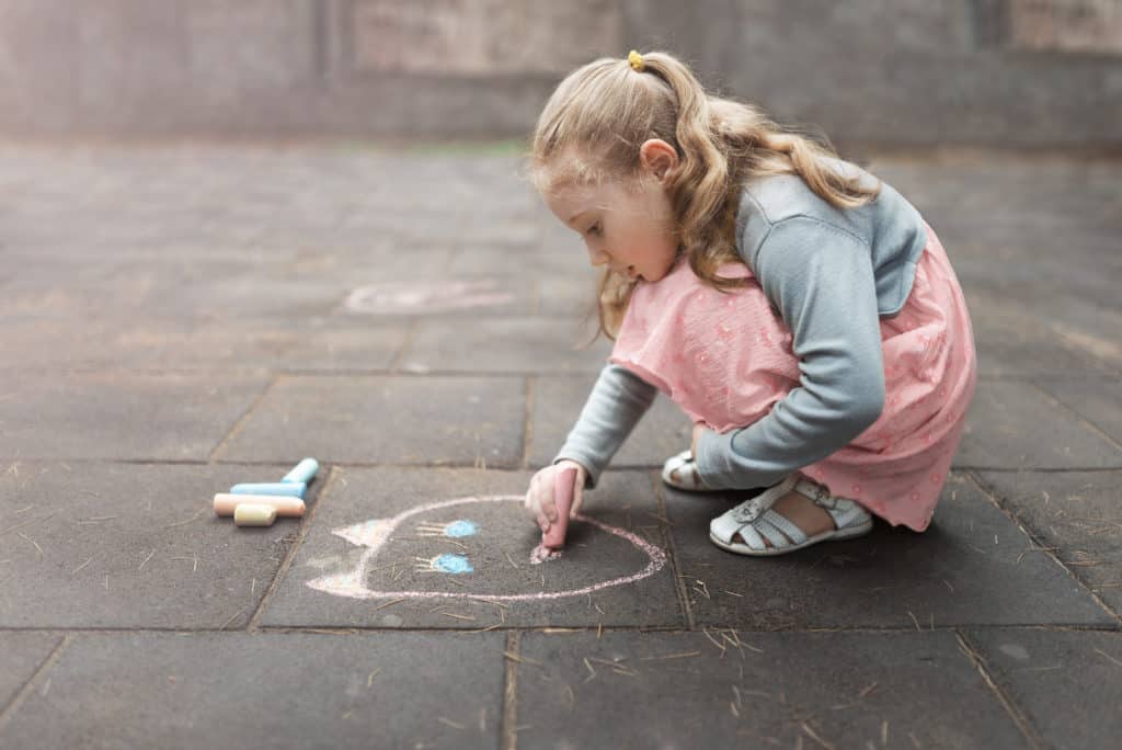 Little Girl Draws a Chalk on Asphalt