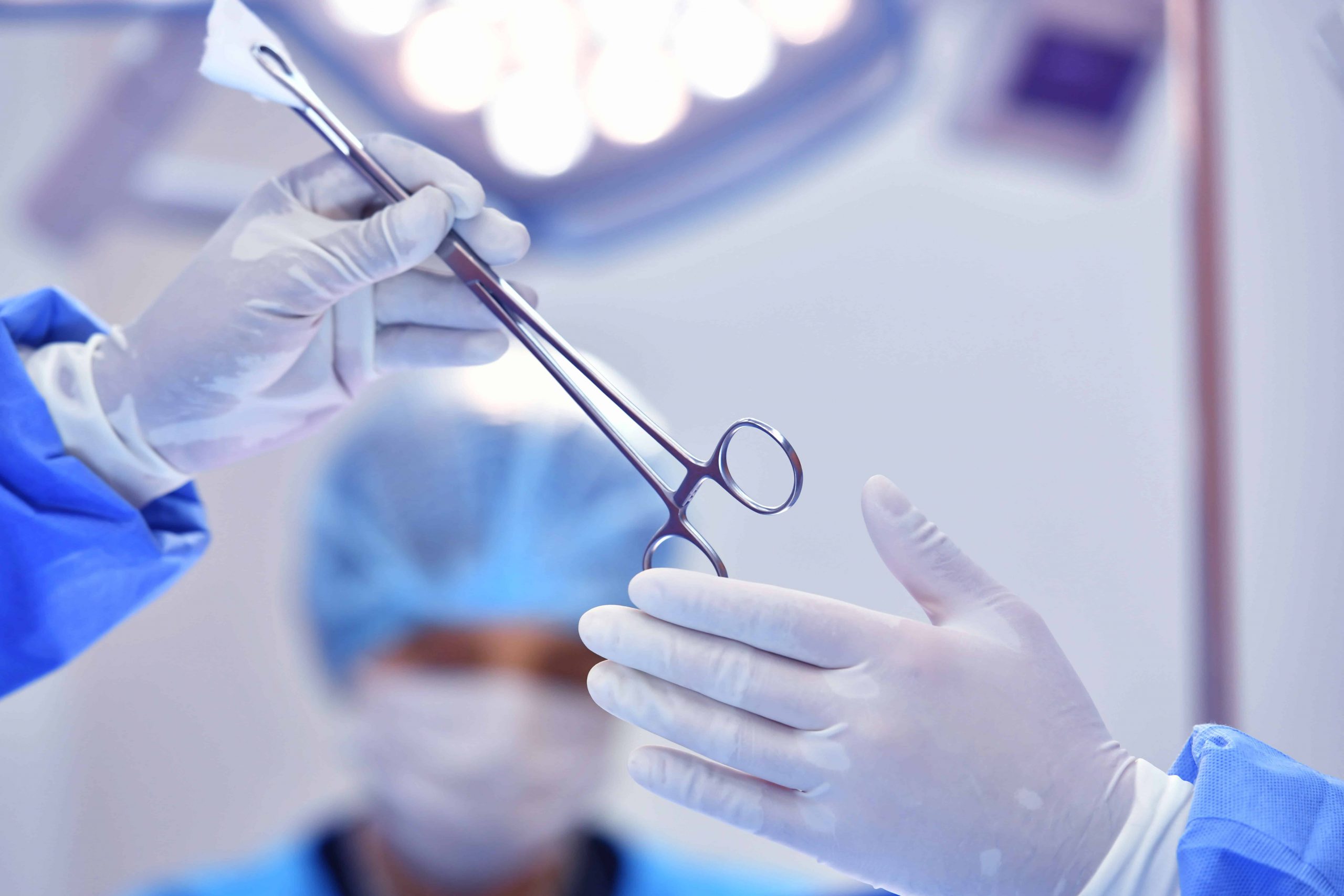 Closeup of a surgical tech handing a surgeon a tool