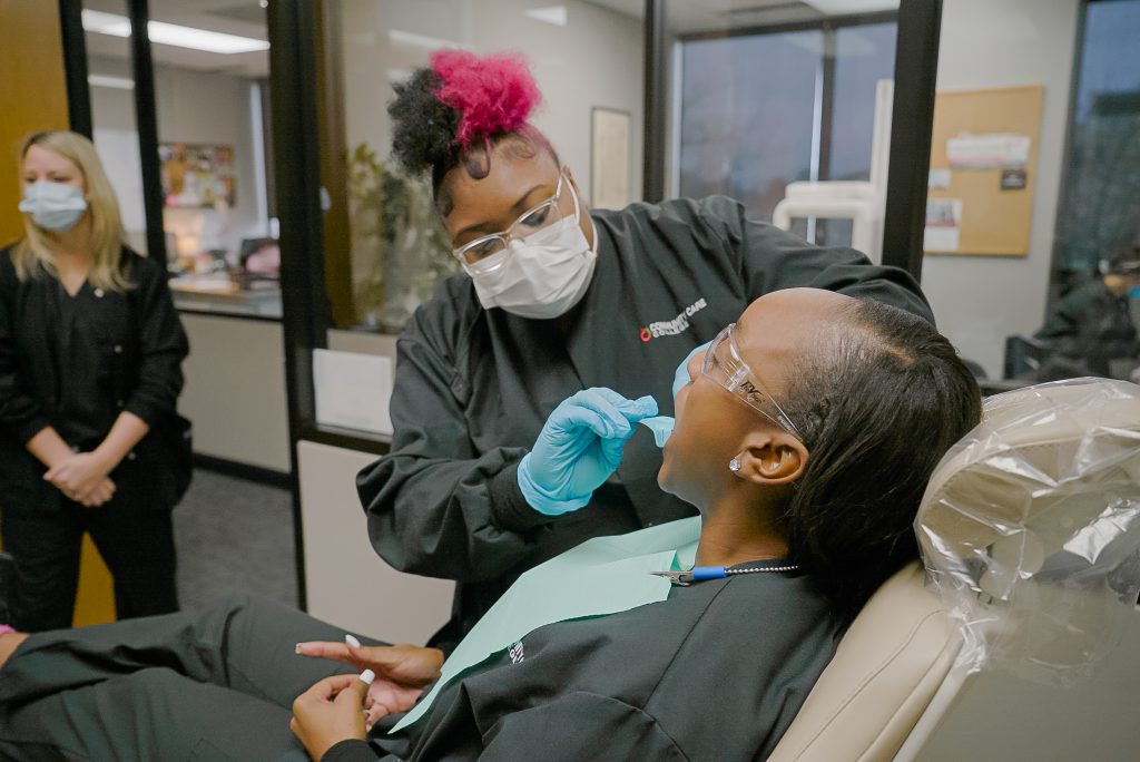 A female dental assistant is working on a patient